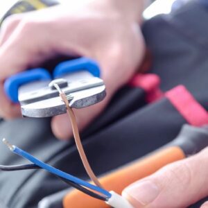 Hand using pliers to strip wire.