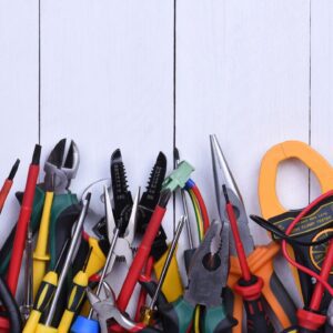 Assorted electrical tools on white wooden background.